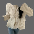Beige loose-fit knit sweater with frill trim, worn as cozy autumn/winter outerwear